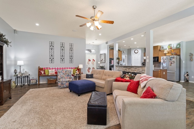 living room featuring a textured ceiling, dark hardwood / wood-style floors, and ceiling fan