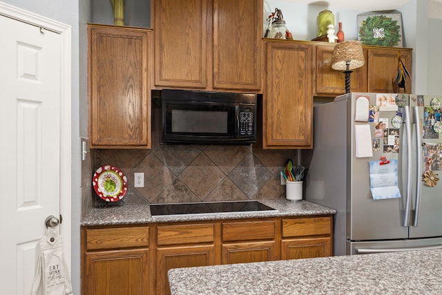 kitchen featuring tasteful backsplash, light stone counters, and black appliances