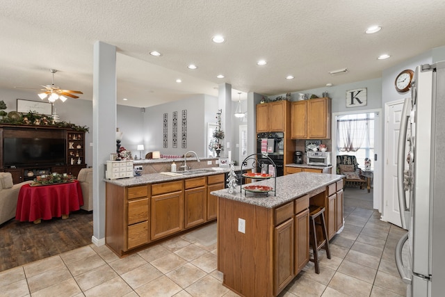 kitchen featuring sink, ceiling fan, a kitchen island, white fridge, and kitchen peninsula