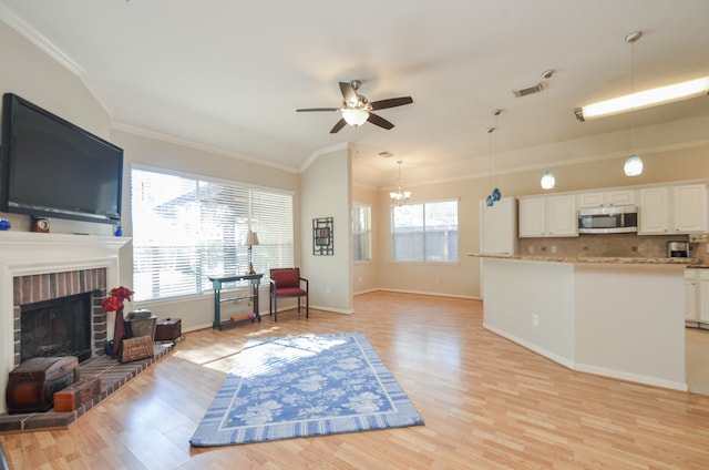 living room featuring crown molding, light hardwood / wood-style flooring, a healthy amount of sunlight, and ceiling fan with notable chandelier