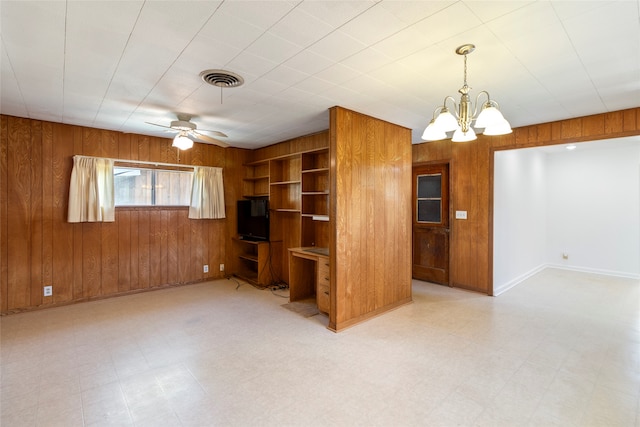 unfurnished living room featuring wood walls and ceiling fan with notable chandelier