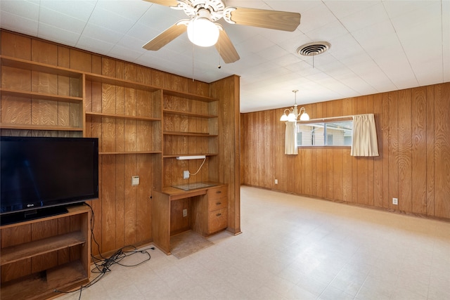 living room featuring wood walls and ceiling fan with notable chandelier