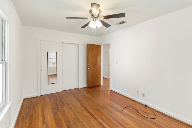 unfurnished bedroom with wood-type flooring, a closet, and ceiling fan