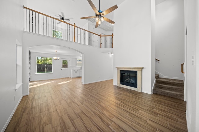 unfurnished living room featuring ceiling fan, a fireplace, a high ceiling, and hardwood / wood-style flooring