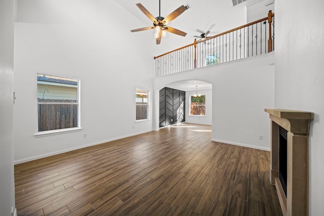 unfurnished living room featuring ceiling fan, dark hardwood / wood-style flooring, and a high ceiling