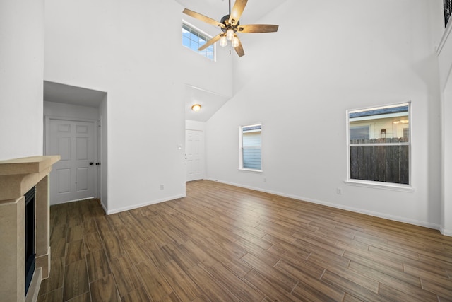 unfurnished living room featuring ceiling fan, dark hardwood / wood-style flooring, and a high ceiling