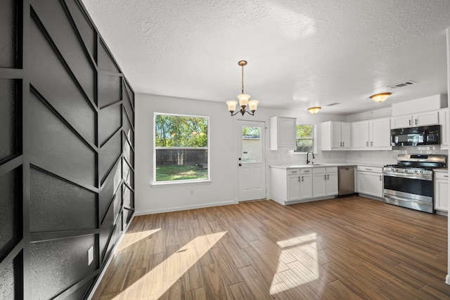 kitchen with stainless steel appliances, white cabinetry, and hardwood / wood-style flooring