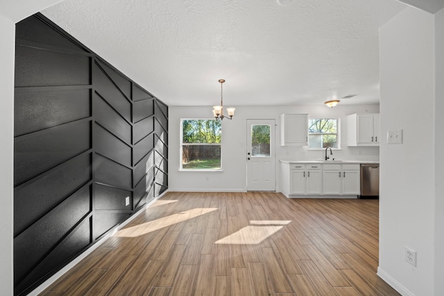 foyer featuring sink, light hardwood / wood-style floors, a textured ceiling, and a notable chandelier