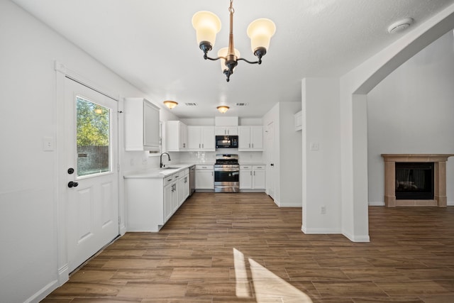 kitchen featuring hardwood / wood-style flooring, white cabinetry, appliances with stainless steel finishes, and an inviting chandelier