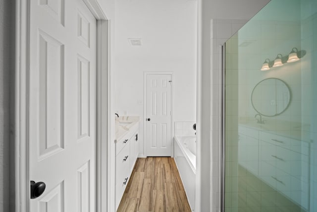 bathroom with hardwood / wood-style floors, vanity, and shower with separate bathtub