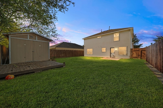 back house at dusk with a yard and a storage unit