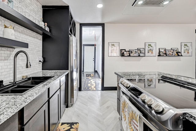 kitchen featuring decorative backsplash, appliances with stainless steel finishes, light stone countertops, and sink