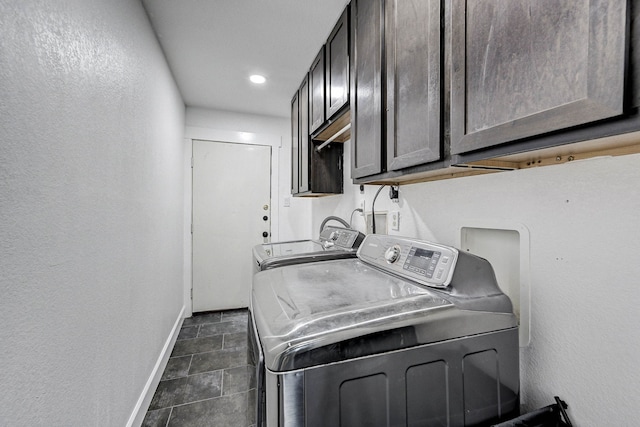 washroom featuring washing machine and clothes dryer, dark tile patterned floors, and cabinets