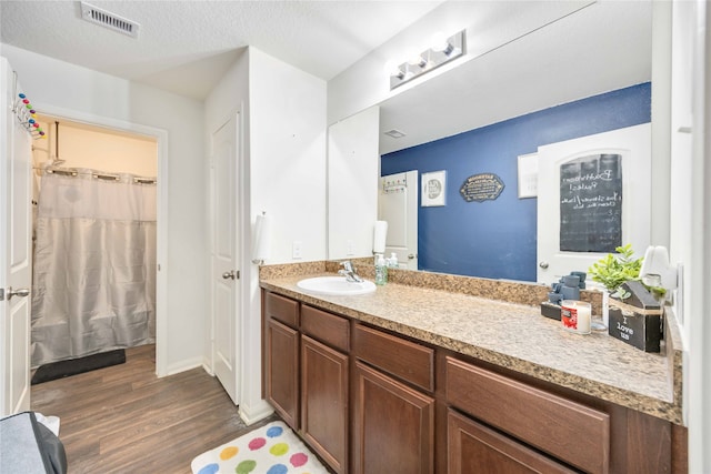 bathroom with hardwood / wood-style floors, vanity, a textured ceiling, and walk in shower