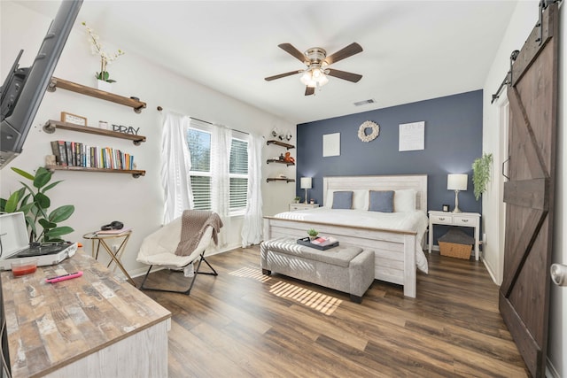 bedroom featuring a barn door, ceiling fan, and dark hardwood / wood-style flooring