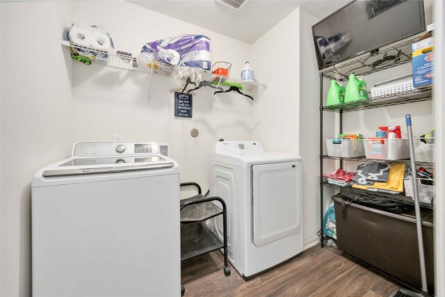 washroom with washer and dryer and dark wood-type flooring