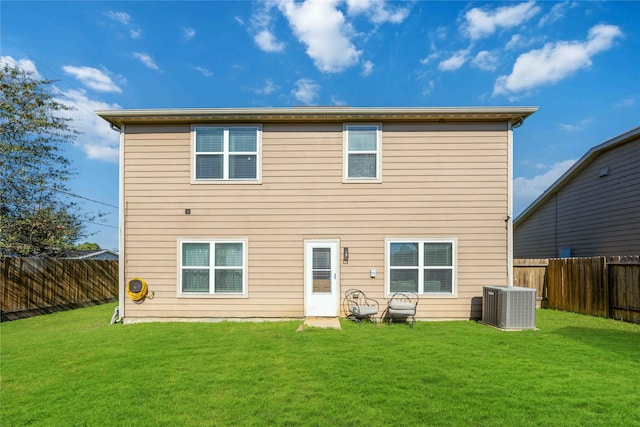 rear view of house with cooling unit and a yard