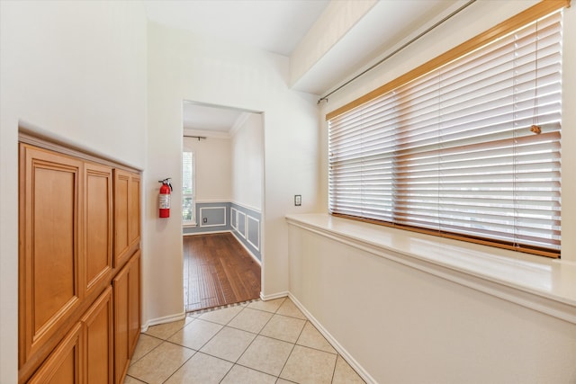 hallway featuring plenty of natural light, light tile patterned floors, and ornamental molding