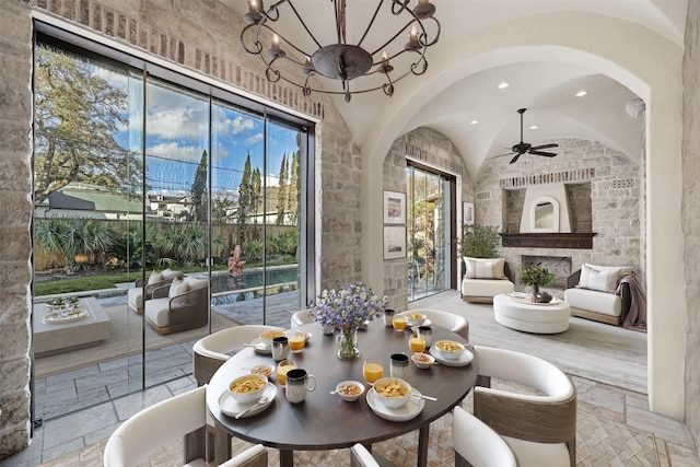 dining area featuring ceiling fan with notable chandelier and vaulted ceiling