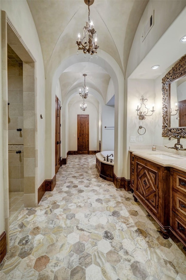 bathroom with vanity, vaulted ceiling, a tub, and a chandelier