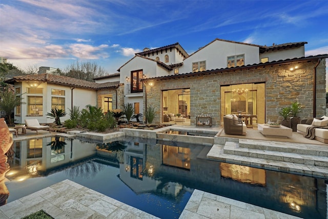 back house at dusk featuring an outdoor living space with a fire pit and a patio