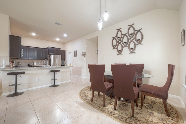 tiled dining room with lofted ceiling and sink