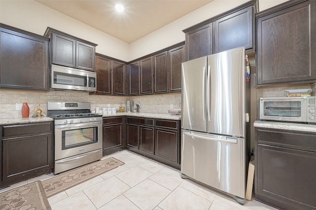 kitchen featuring light stone countertops, dark brown cabinets, backsplash, and stainless steel appliances