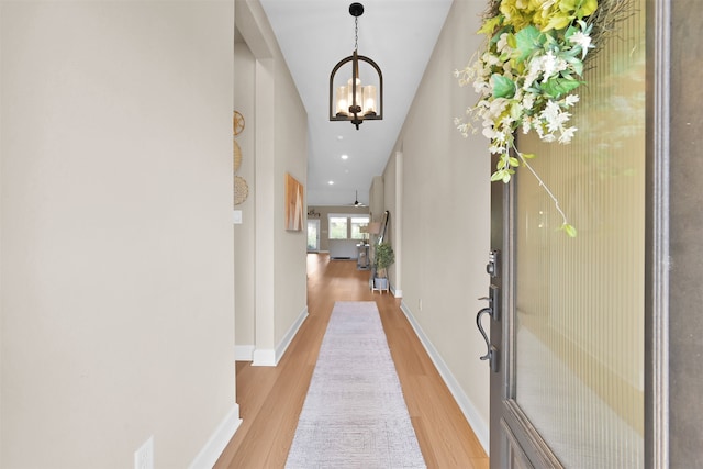 hallway featuring an inviting chandelier and light hardwood / wood-style flooring