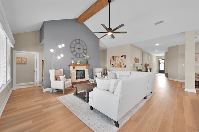 living room featuring beam ceiling, ceiling fan, light hardwood / wood-style flooring, high vaulted ceiling, and a fireplace