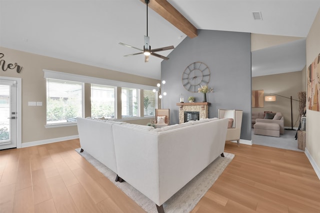 living room featuring a fireplace, vaulted ceiling with beams, light hardwood / wood-style flooring, and plenty of natural light