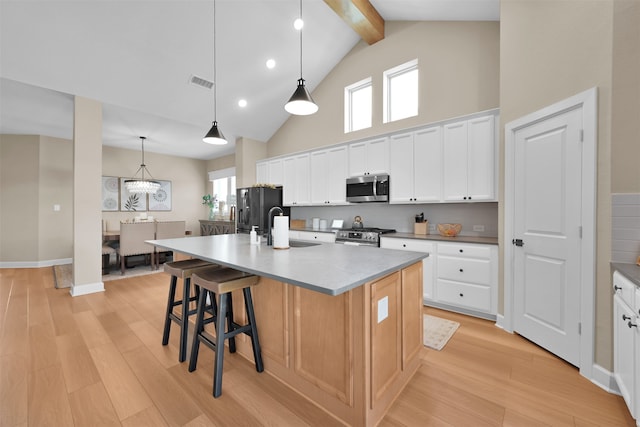 kitchen featuring white cabinets, appliances with stainless steel finishes, a center island with sink, and light hardwood / wood-style floors