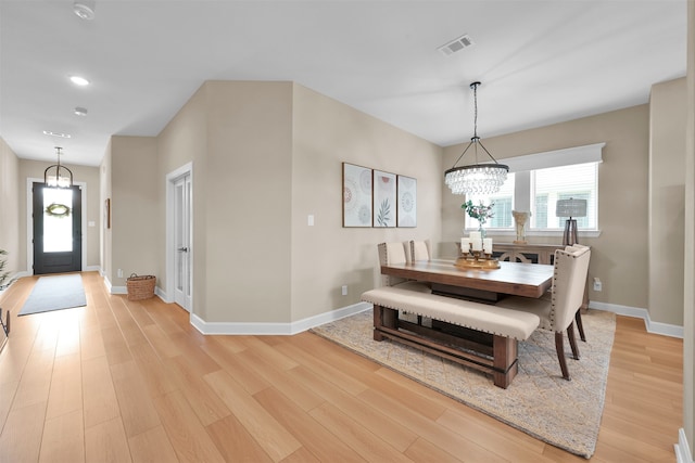 dining room with light hardwood / wood-style floors and a chandelier