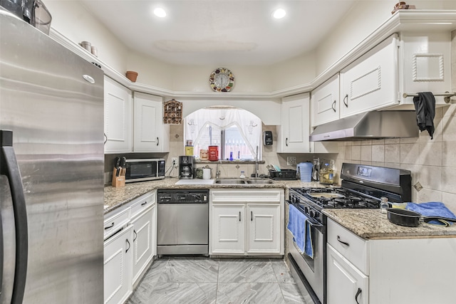 kitchen featuring backsplash, white cabinets, sink, light stone countertops, and appliances with stainless steel finishes