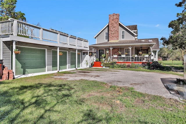 rear view of property featuring a yard, covered porch, and a garage