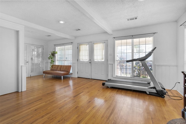 entrance foyer with plenty of natural light, beamed ceiling, light hardwood / wood-style floors, and a textured ceiling