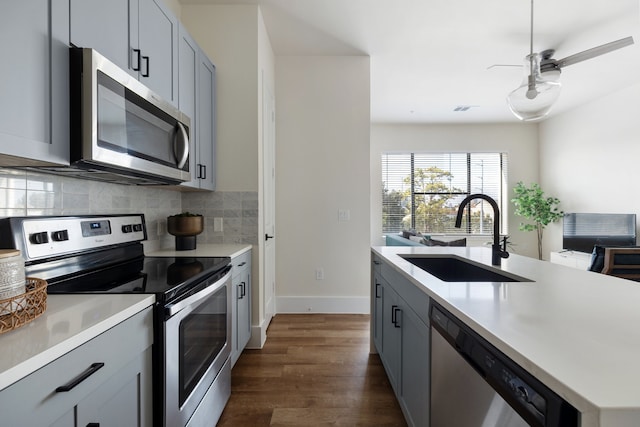 kitchen featuring dark wood-type flooring, sink, gray cabinetry, and stainless steel appliances