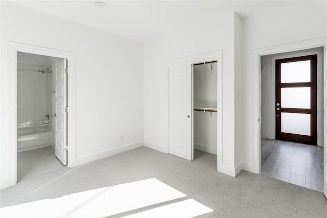 unfurnished bedroom with light colored carpet, connected bathroom, and a closet