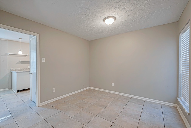 empty room with light tile patterned floors and a textured ceiling