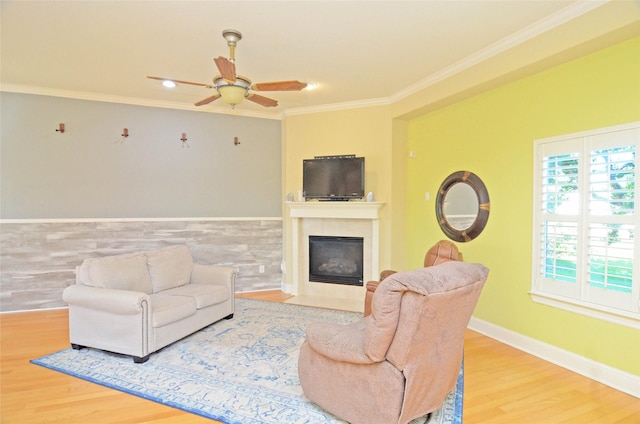 living room featuring a tile fireplace, hardwood / wood-style floors, crown molding, and ceiling fan