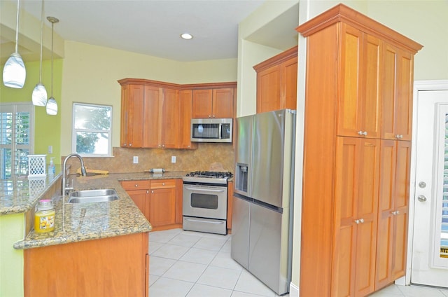 kitchen featuring sink, light tile patterned floors, stainless steel appliances, and hanging light fixtures