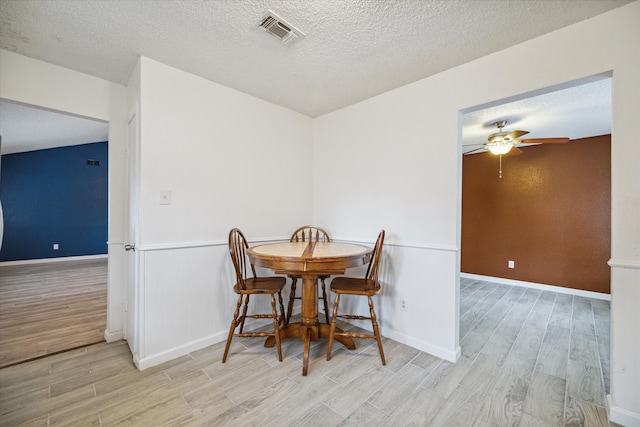 dining area with ceiling fan, a textured ceiling, and light hardwood / wood-style flooring