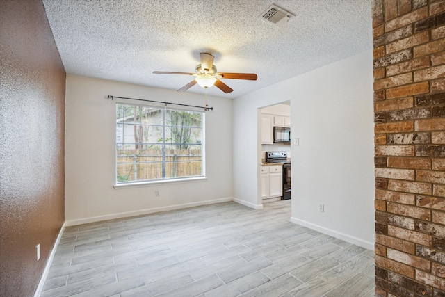 spare room with ceiling fan, a textured ceiling, and light wood-type flooring