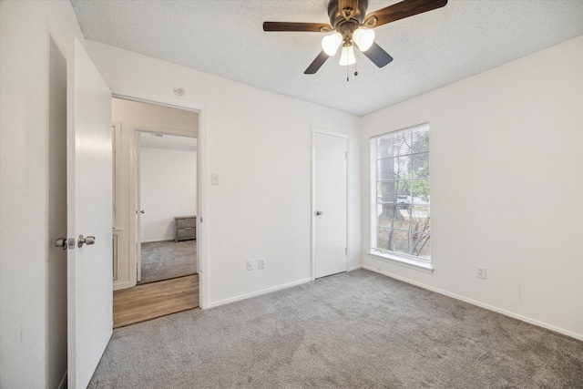 unfurnished bedroom with ceiling fan, light colored carpet, and a textured ceiling