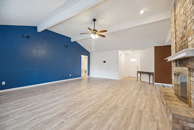 unfurnished living room featuring lofted ceiling with beams, light hardwood / wood-style floors, a fireplace, and ceiling fan