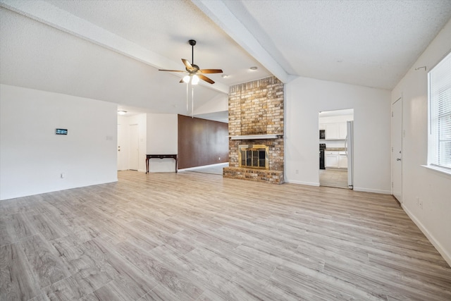 unfurnished living room with ceiling fan, vaulted ceiling with beams, light hardwood / wood-style floors, a textured ceiling, and a fireplace