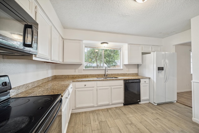 kitchen with black appliances, light hardwood / wood-style floors, white cabinets, and sink