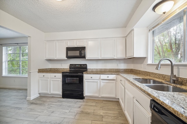 kitchen featuring black appliances, sink, light stone countertops, a textured ceiling, and white cabinetry