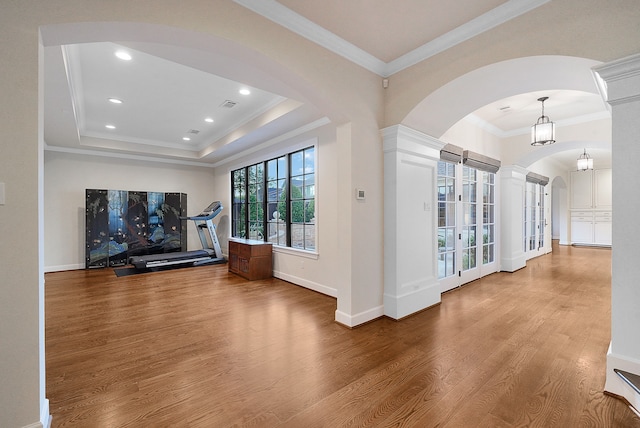 interior space with hardwood / wood-style floors, a raised ceiling, crown molding, and an inviting chandelier