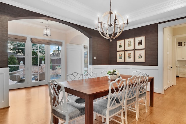 dining room with french doors, light hardwood / wood-style floors, an inviting chandelier, and crown molding