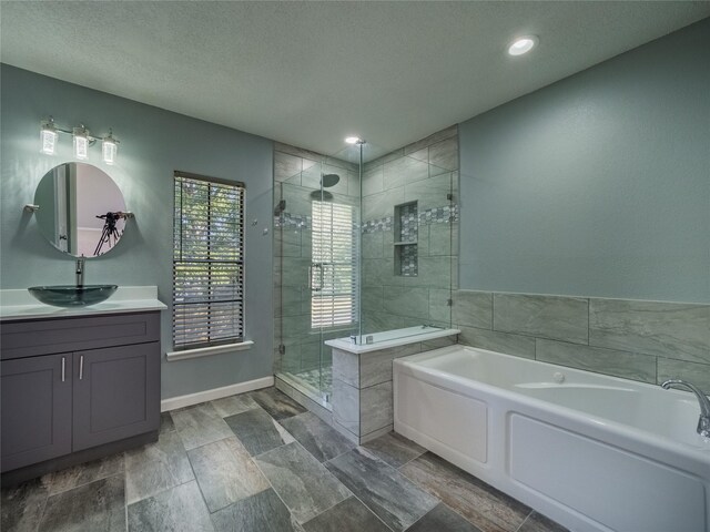 bathroom with a textured ceiling, vanity, and independent shower and bath